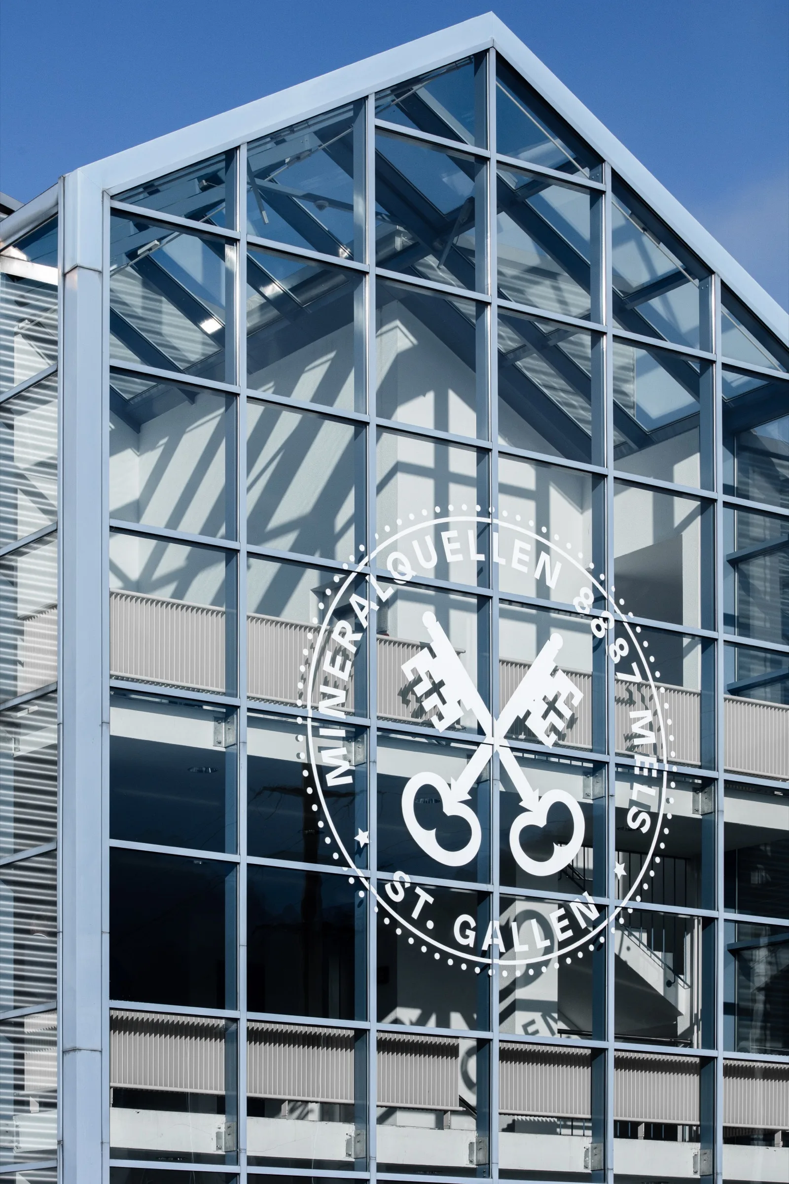Glasfassade der Mineralquellen Mels mit graviertem Wappen